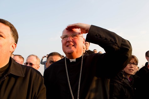 New York Cardinal Timothy Dolan watches as the helicopter carrying Pope Benedict lifts off from the Vatican grounds February 28.  Pilot photo/Gregory L. Tracy